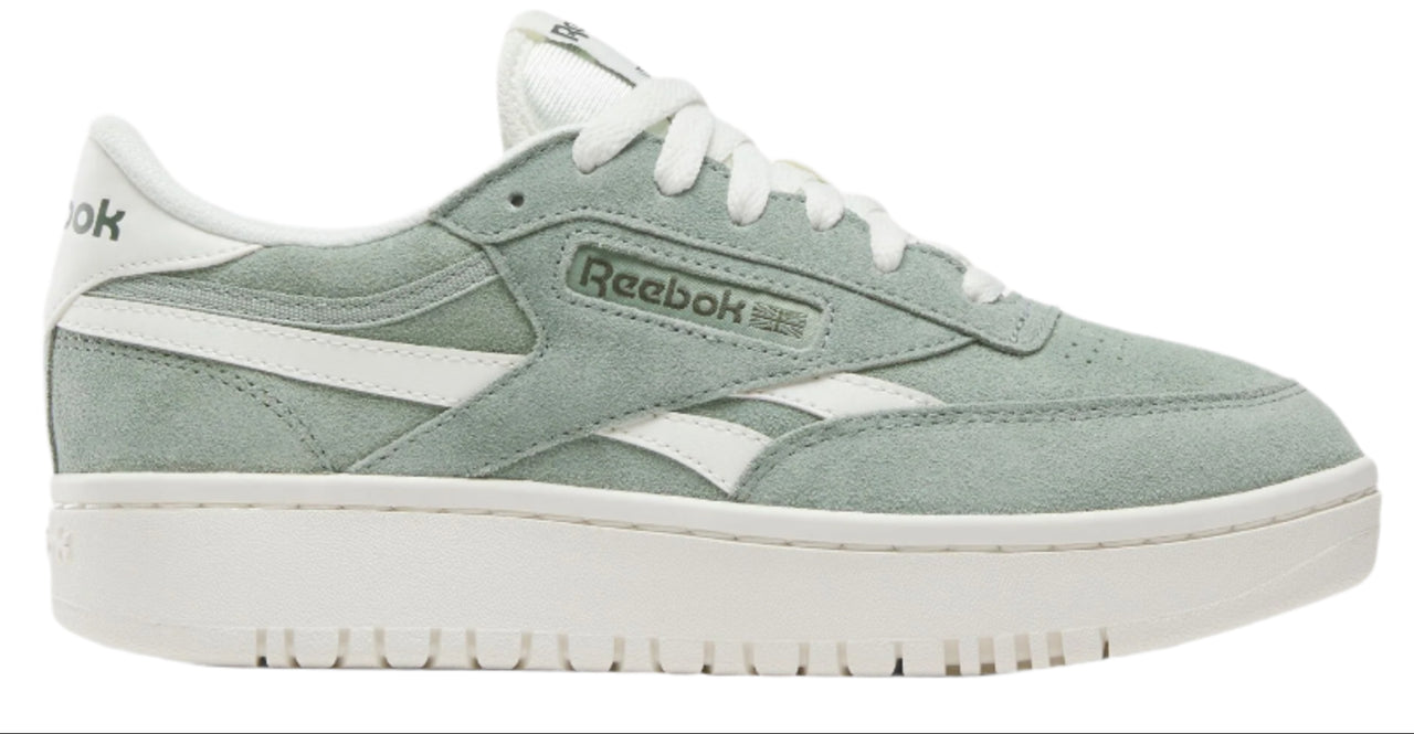 A low top light green sneaker with white laces and a white stripe that has the text "Reebok" on it, atop a thick white sole.