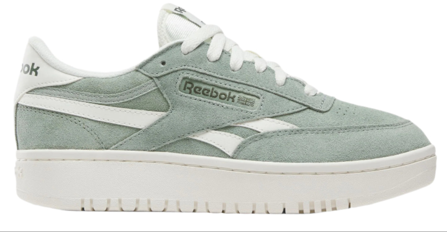 A low top light green sneaker with white laces and a white stripe that has the text "Reebok" on it, atop a thick white sole.