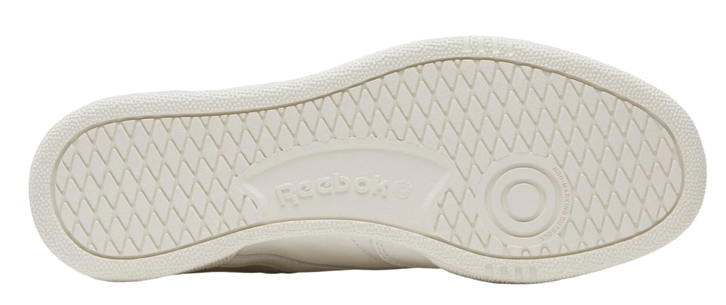 The bottom of a light tan sneaker with a criss-cross traction pattern, and the word "Reebok" is in a small indentation.