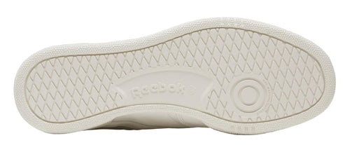 The bottom of a light tan sneaker with a criss-cross traction pattern, and the word "Reebok" is in a small indentation.