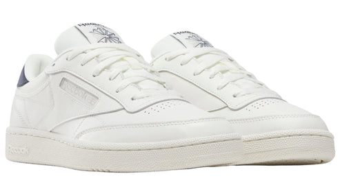 Pair of low-cut, all-white sneakers with navy blue accent on the heel.