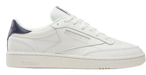 A white low-top sneaker with a navy blue heel.