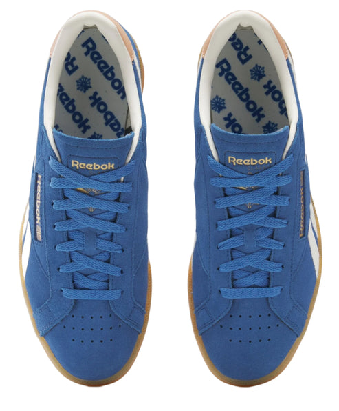 Two blue suede sneakers with white stripe and light brown rubber sole. The inside is white with repeating blue text.