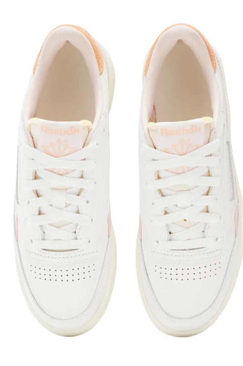 Top-down view of a pair of white sneakers with peach detailing and white laces.