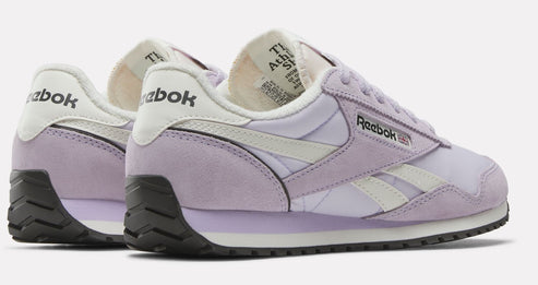 Low profile shoe with lavender and white upper and black sole, “Reebok” logo on the side and heel.