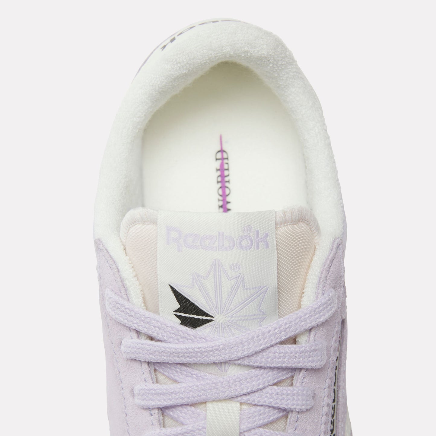 Close-up of a light purple shoe with white laces, a white insole, and a tongue featuring the text "Reebok" and a logo, with "WORLD" vertically printed on the insole.