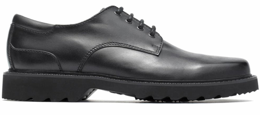 A black dress shoe with a thick, lugged sole and a lace-up closure.