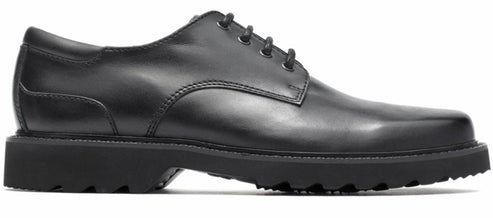 A black dress shoe with a thick, lugged sole and a lace-up closure.