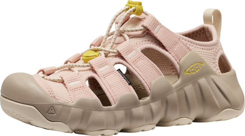 Side view of a light pink sandal with beige accents, featuring a rounded toe, rope laces, adjustable straps, and thick ridged sole.