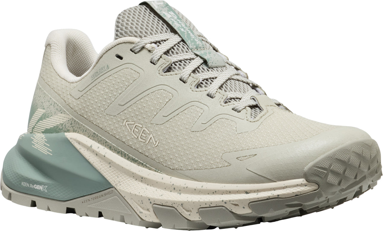A low-profile, light beige trail running shoe with a light gray mesh upper, and a contrasting teal heel and tongue.