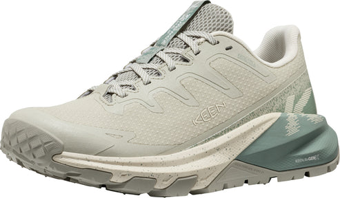 Low top trail running shoe with a beige upper, speckled midsole, and green heel.