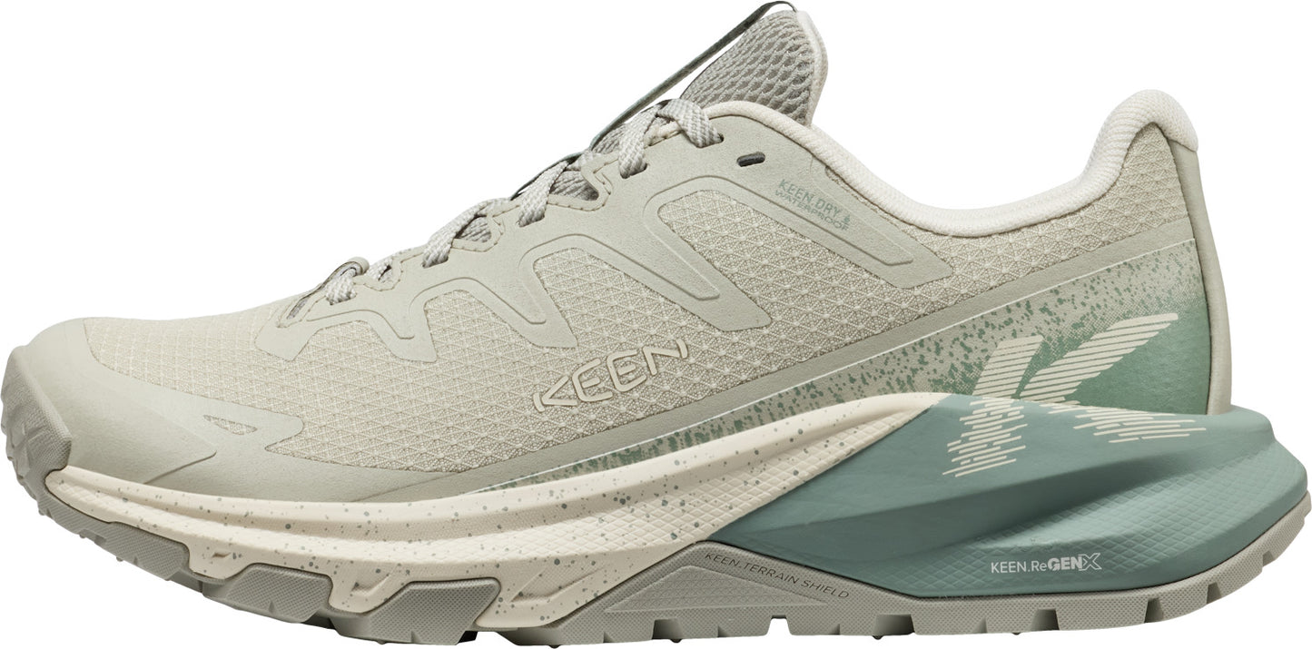 Tan-colored athletic shoe with laces and a green patterned sole.