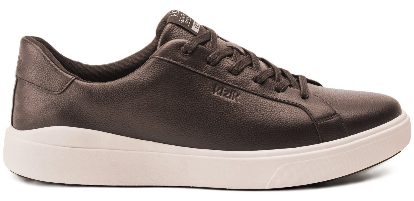 A brown leather sneaker with white soles and the word "RIZIK" printed on its side.