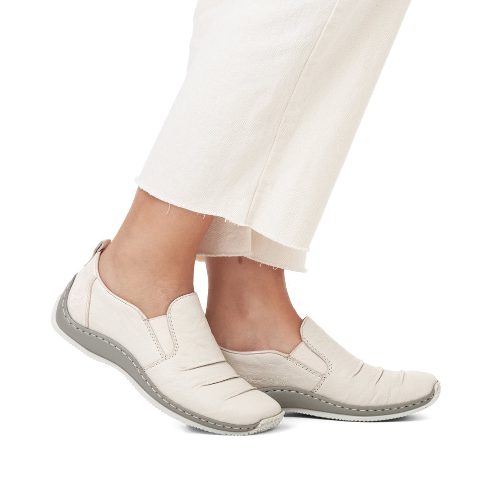 Low top off-white casual slip-on shoes with low profile gray soles on model.