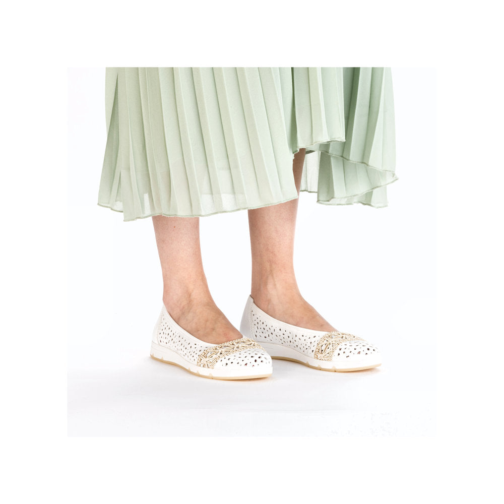 White ballet flat shoes with floral accents, worn with a pleated skirt.