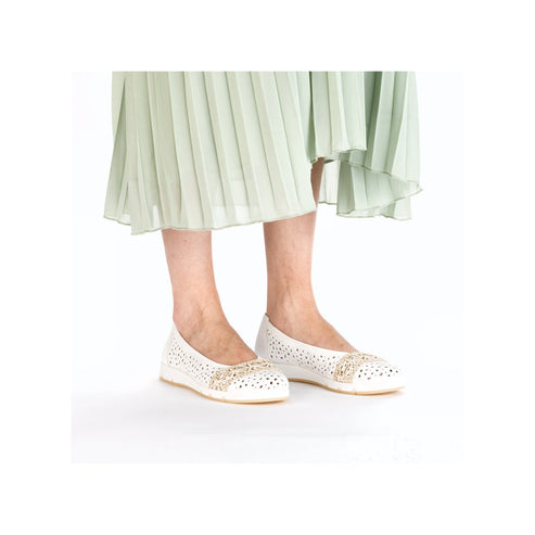 White ballet flat shoes with floral accents, worn with a pleated skirt.