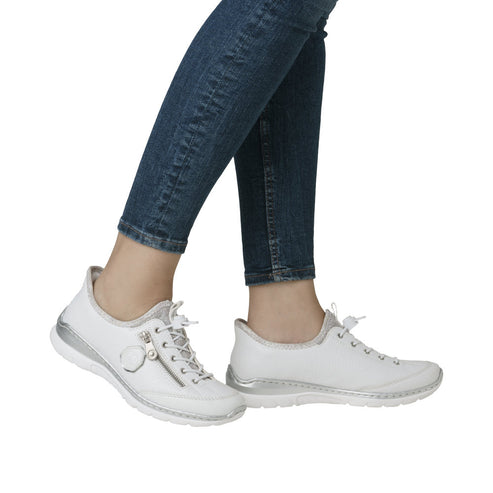 Person wearing blue jeans and white sneakers with silver accents.