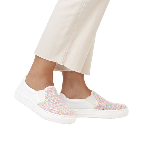 Slip-on sneakers with white soles and rainbow-striped uppers being worn.