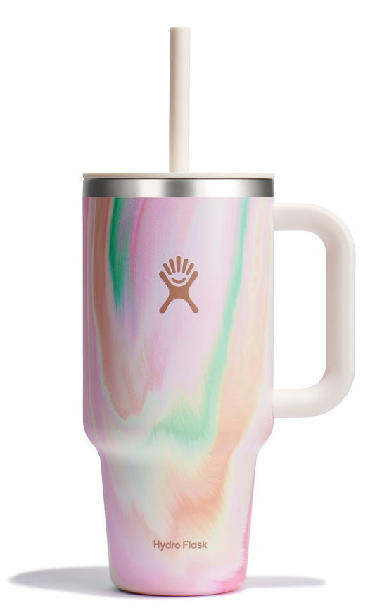 Tall, white handled mug with a lid and straw, decorated with a swirled pattern of pink, orange, and green. The Hydro Flask logo is in the center.