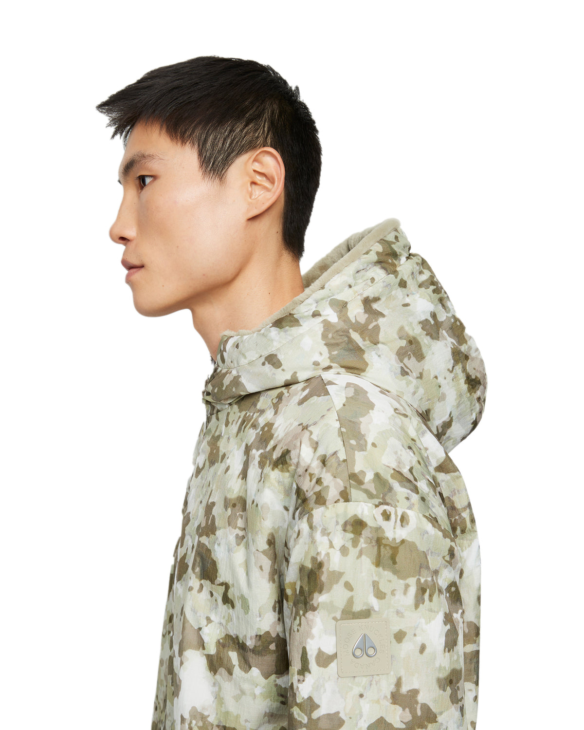 Man in green and white camouflage hooded jacket, side view.