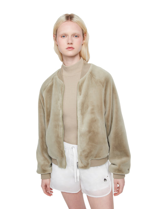 A person wearing a furry light brown jacket with white athletic shorts.