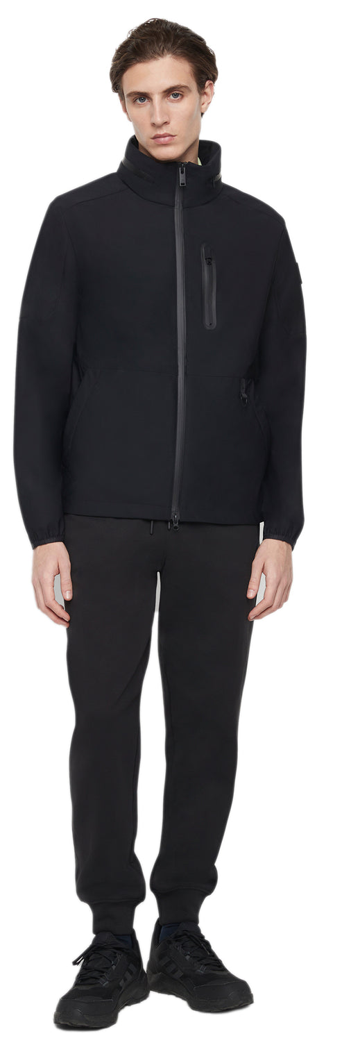 A man wearing a black zip-up jacket, black pants, and black shoes.