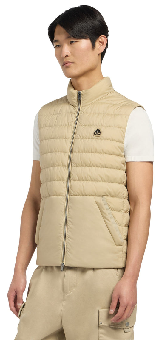 A person wearing a tan puffer vest and tan pants.