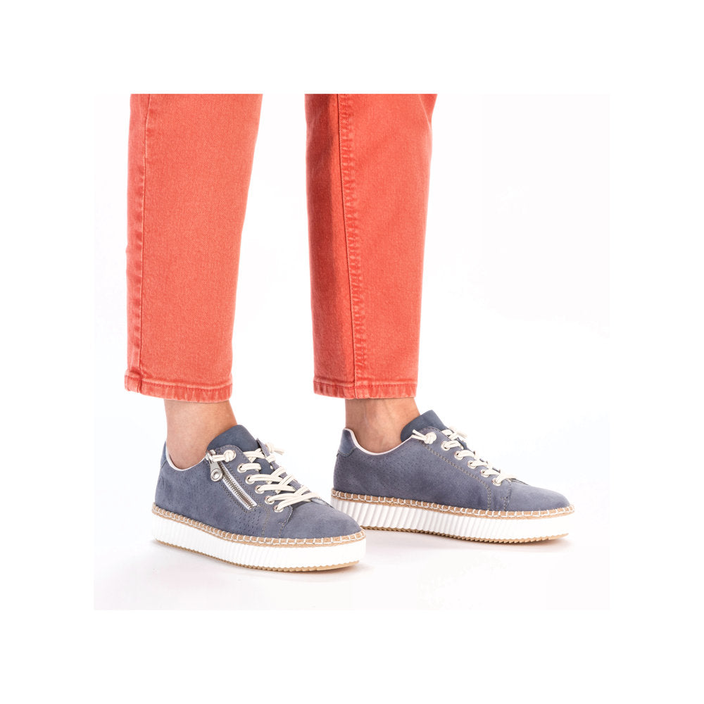 Model wearing casual blue sneakers with zipper detail.