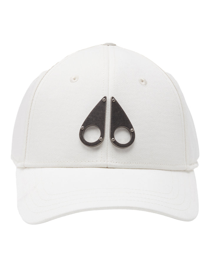 White baseball cap with two metal teardrop shapes with circles and rivets.