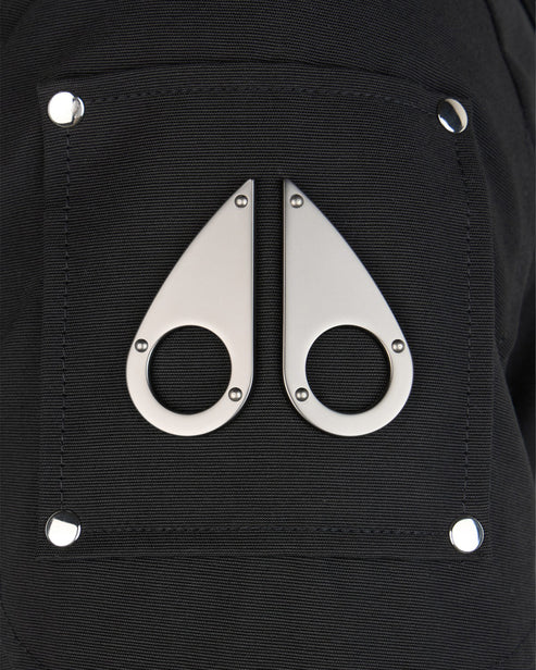 Close-up of black fabric pocket with metal accents; two teardrop shapes with circular holes in the center are oriented vertically.