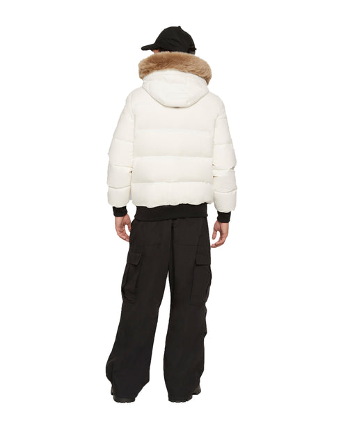 Person wearing white puffer jacket with fur hood, black shirt and cargo pants, rear view.