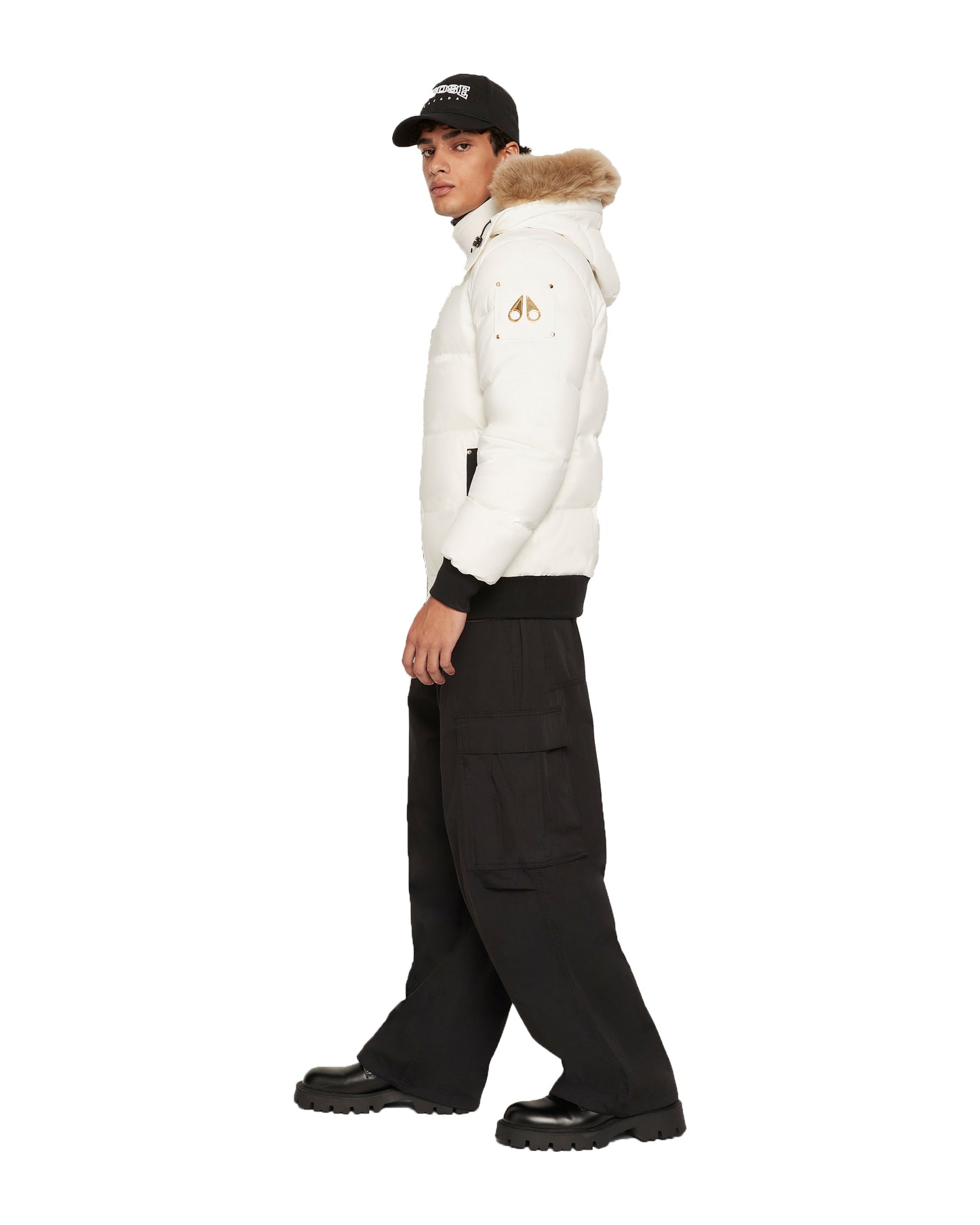 Person wearing a white puffer jacket with a fur-lined hood, black pants, and black boots.