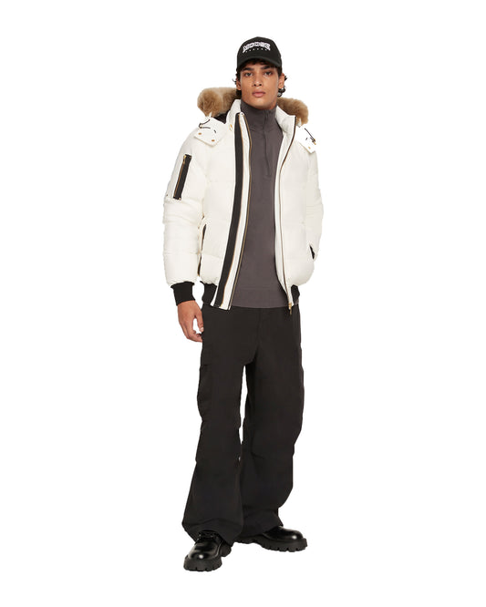 Person in white down bomber jacket with fur hood, black pants, and black baseball cap.