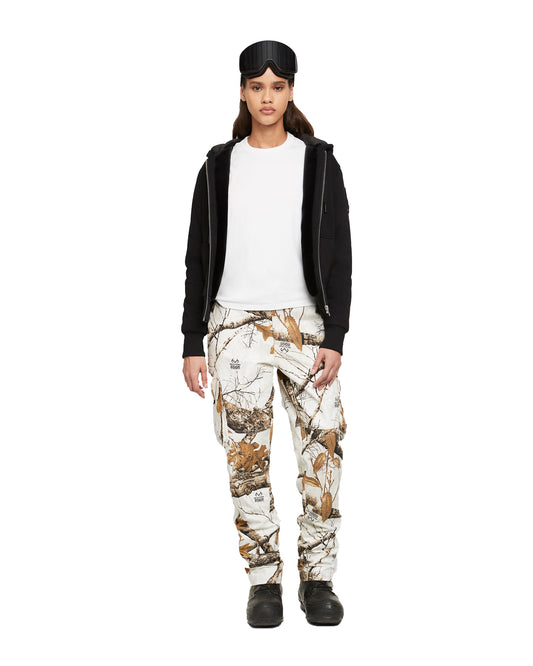 A woman in ski goggles, a black hoodie, a white t-shirt, camouflage pants, and black boots.