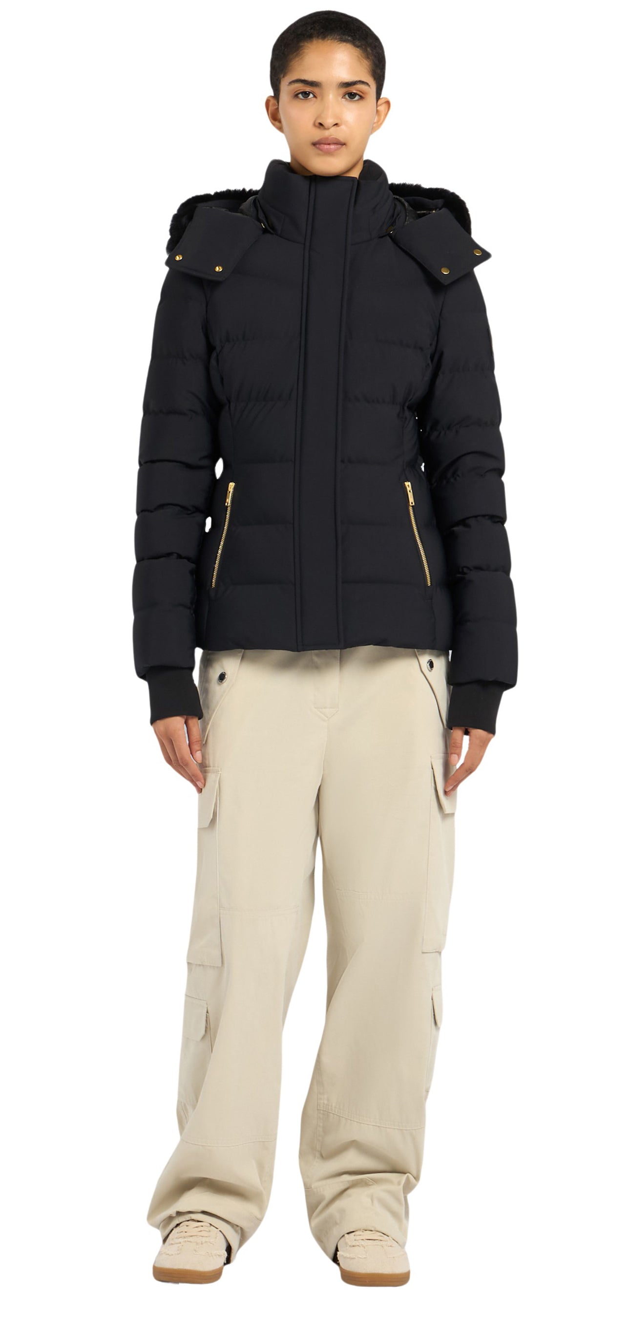 A person wearing a black winter coat and beige pants.