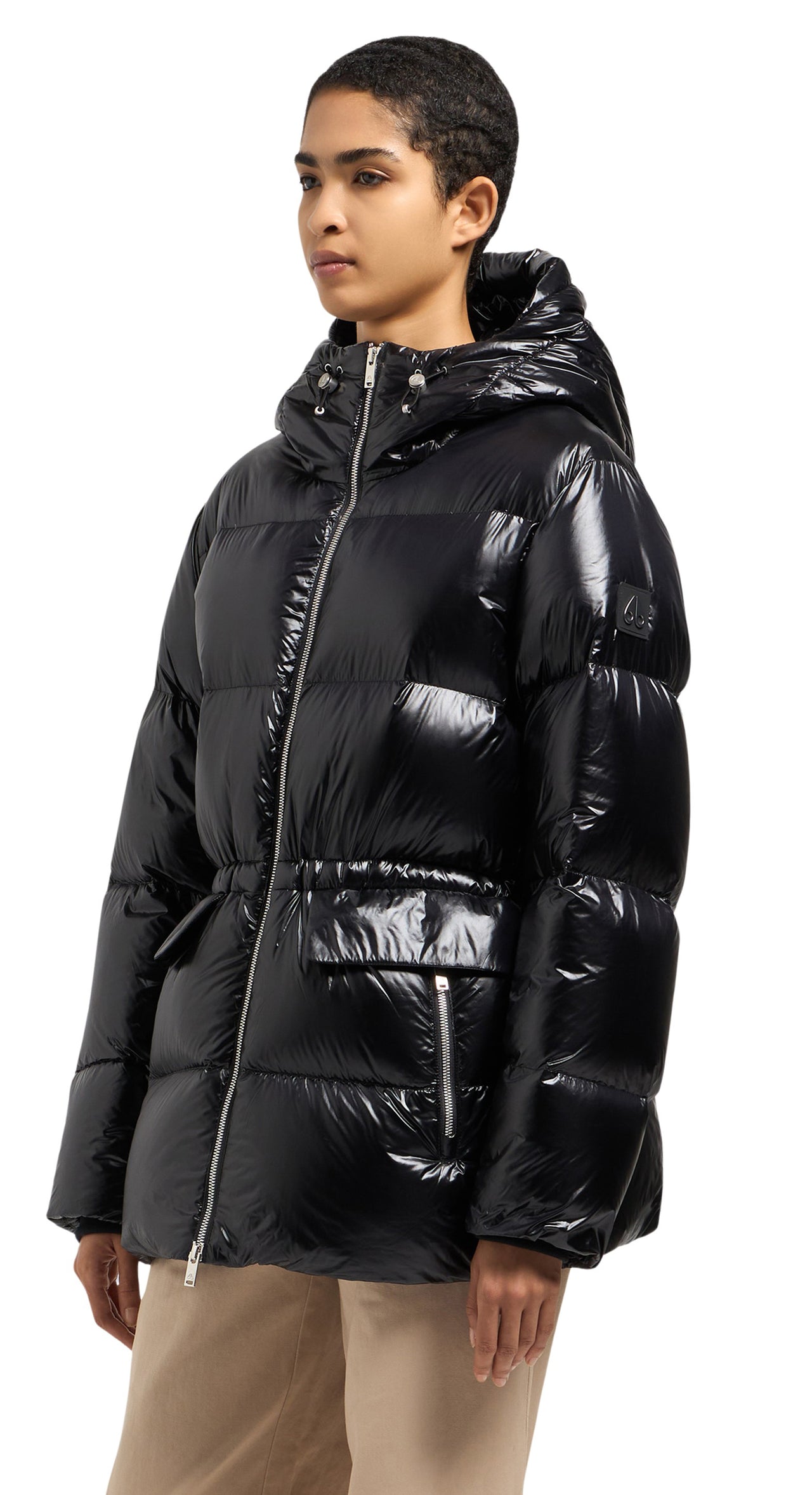A woman wearing a black shiny, puffed-down jacket with a hood and pockets.