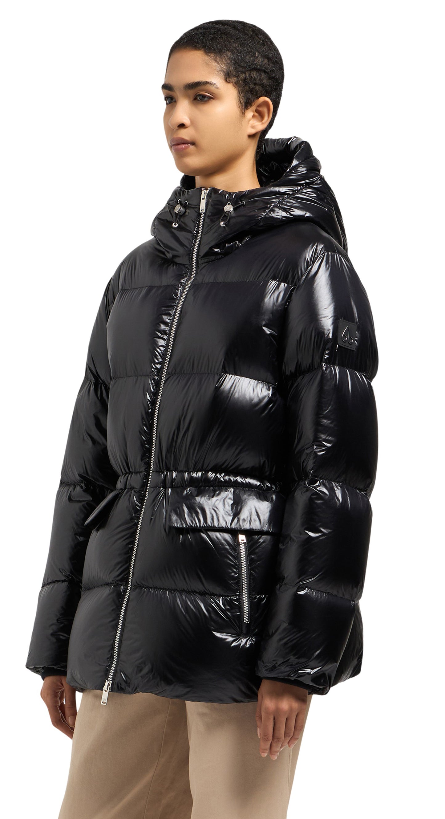 A woman wearing a black shiny, puffed-down jacket with a hood and pockets.