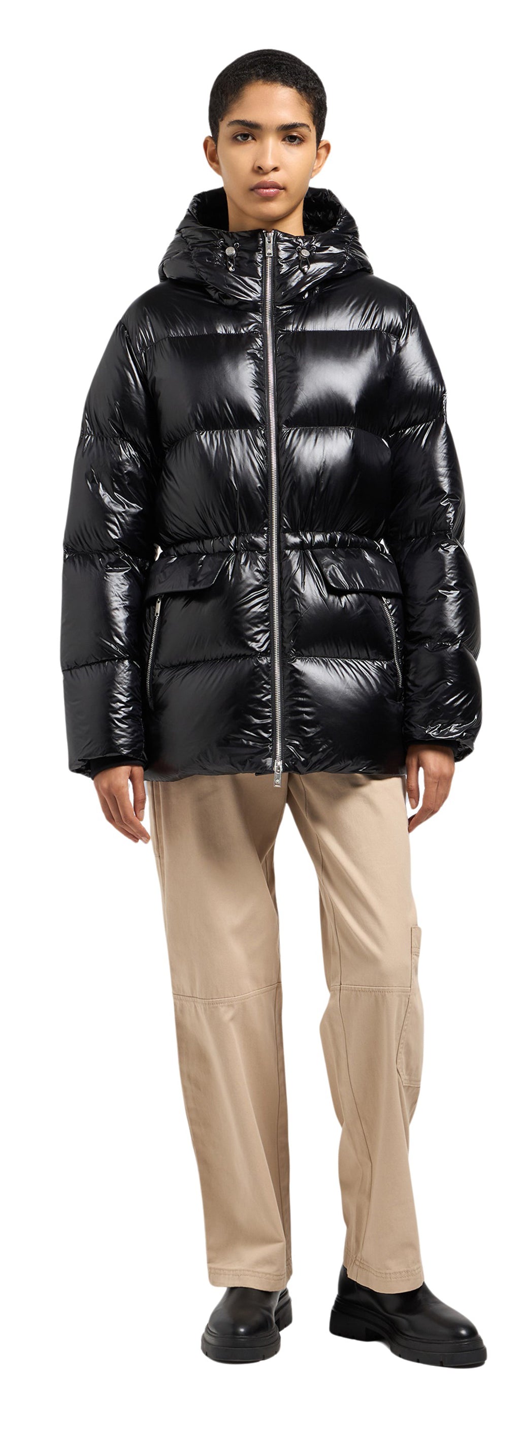 A person wearing a black puffer coat, khaki pants, and black shoes.