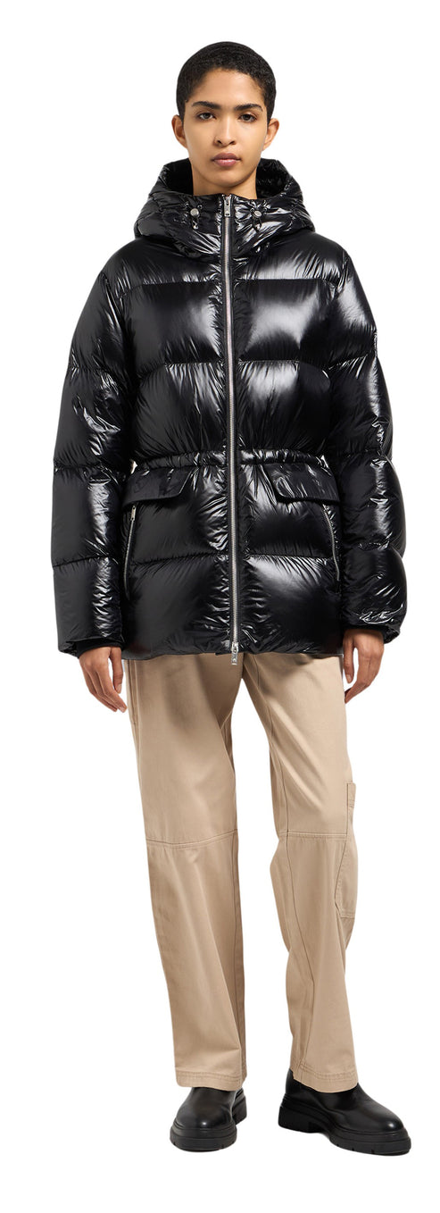 A person wearing a black puffer coat, khaki pants, and black shoes.