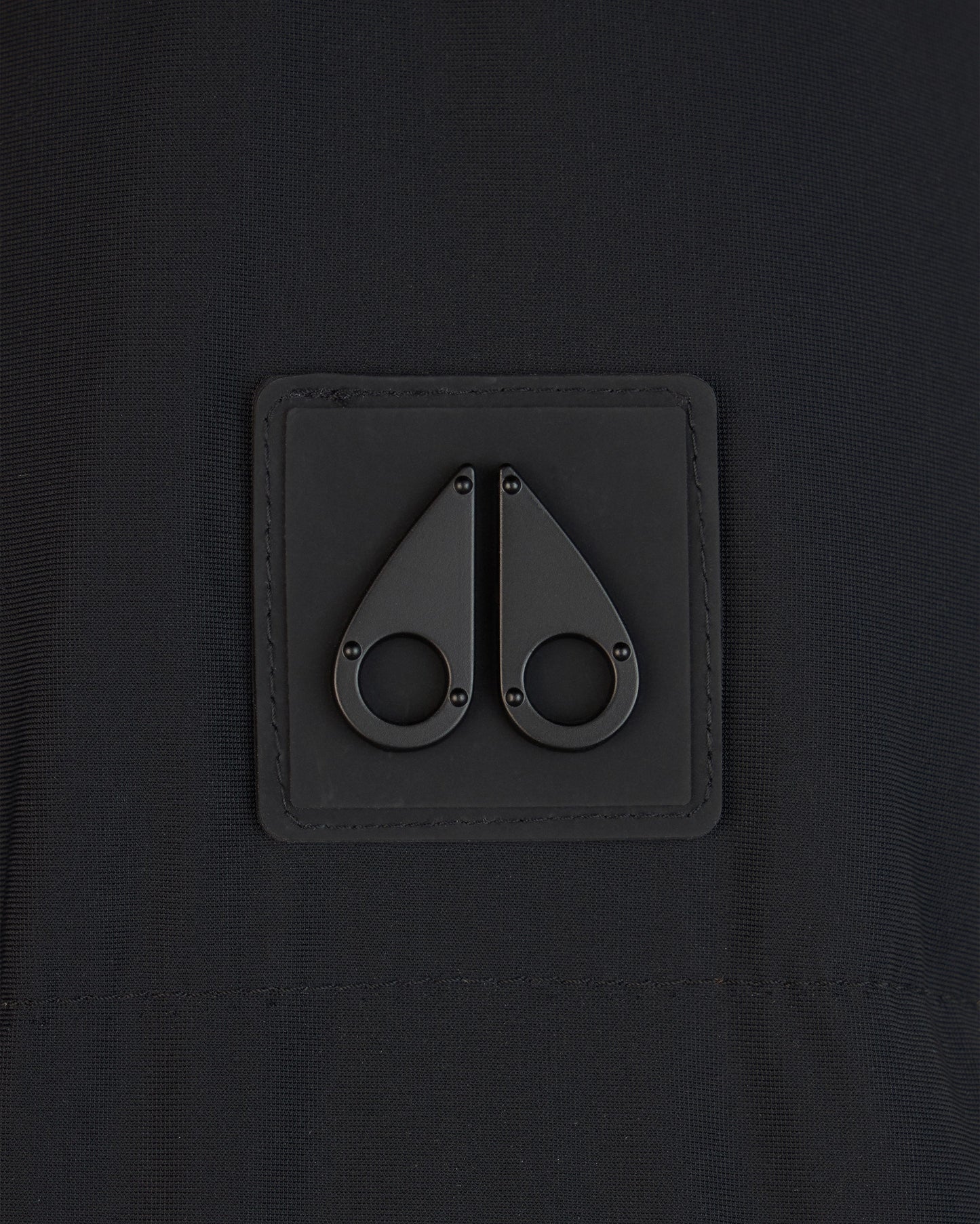 Close-up of a black fabric square with two black metal fastener details.