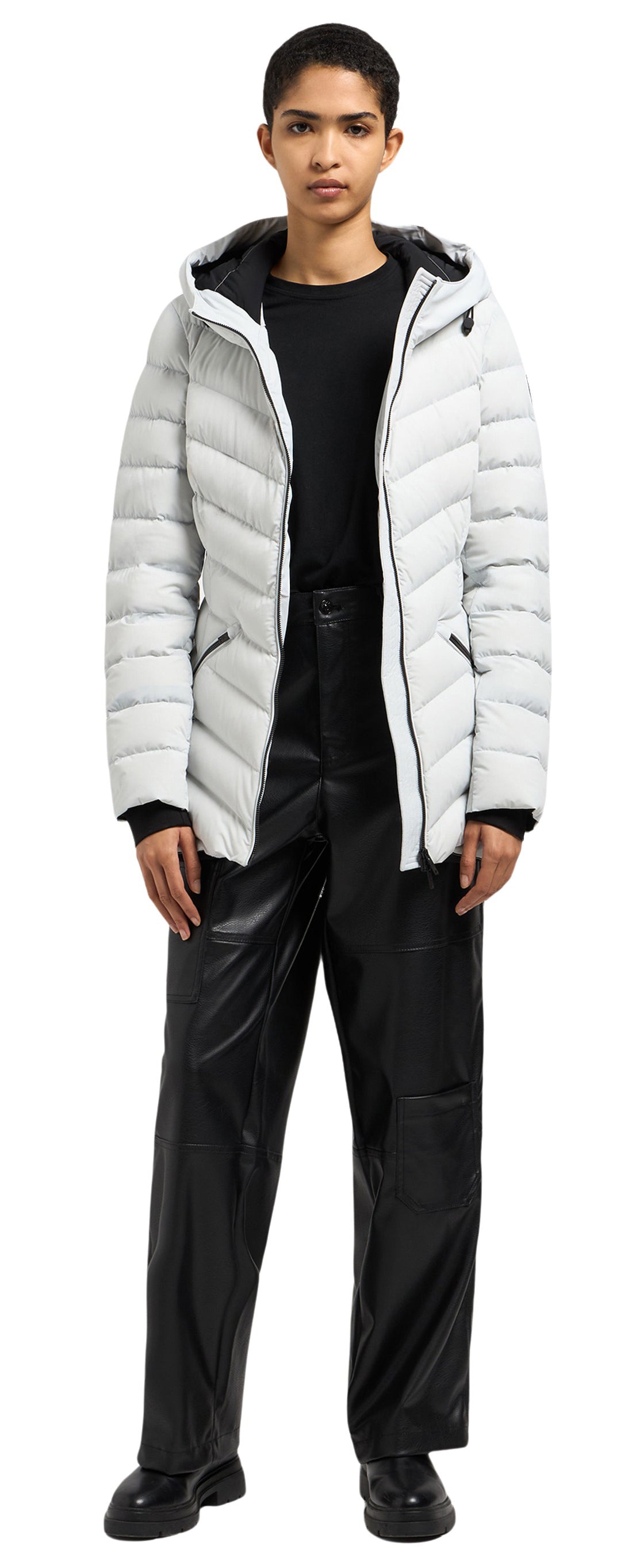 A person wearing a white puffer jacket, black pants and black shoes is standing.