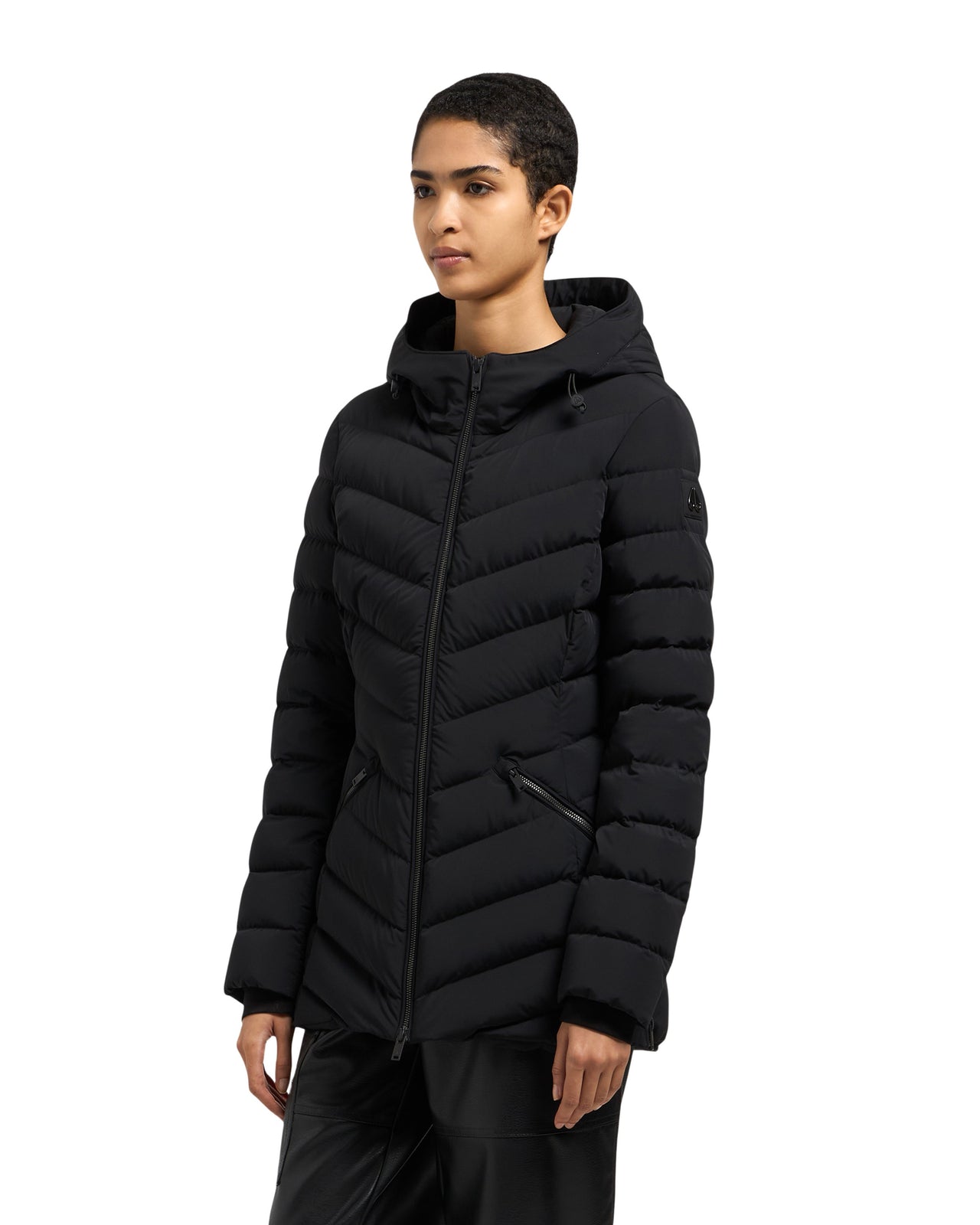 A woman wears a fitted, black puffer jacket with a hood.