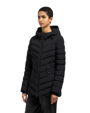 A woman wears a fitted, black puffer jacket with a hood.