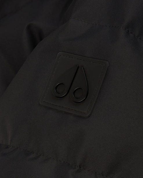 Close-up of a dark garment featuring a small, square patch with a stylized, dark double-scroll logo.