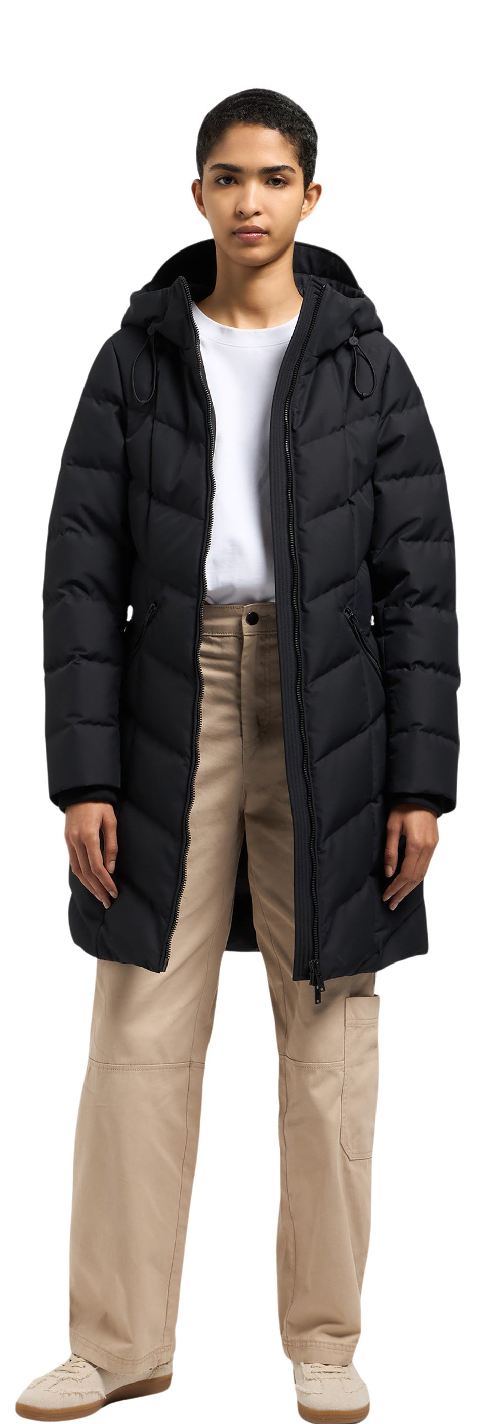 A person wearing a black puffer coat, a white shirt and beige pants.
