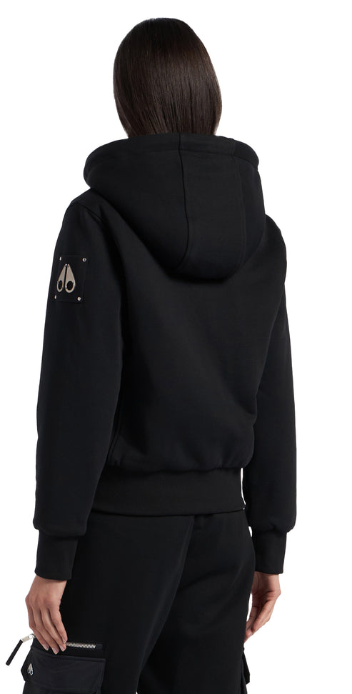 Back view of a person wearing a black hooded sweatshirt with a banded waist, and logo on the left shoulder.