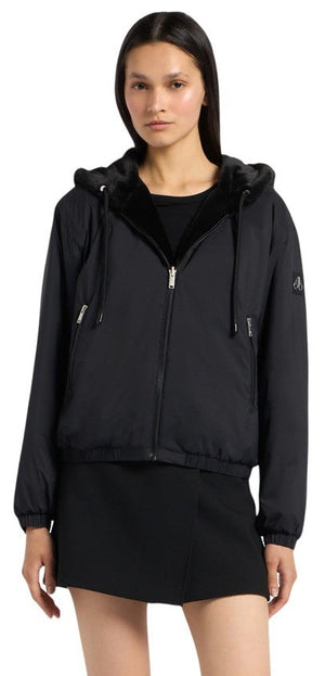 A woman wearing a black hooded jacket and a black skirt.