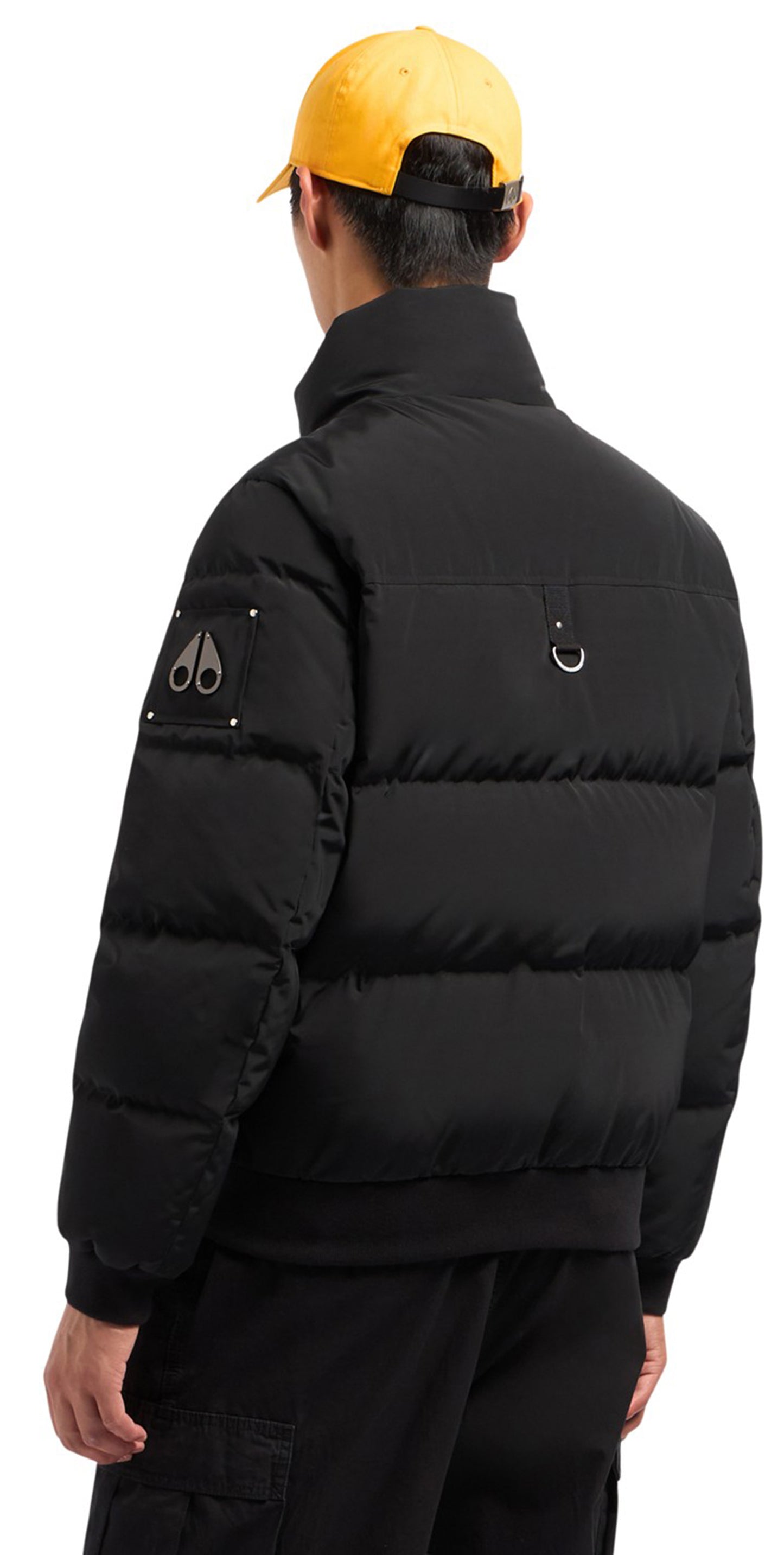 Black puffer jacket with a yellow baseball cap on a person.