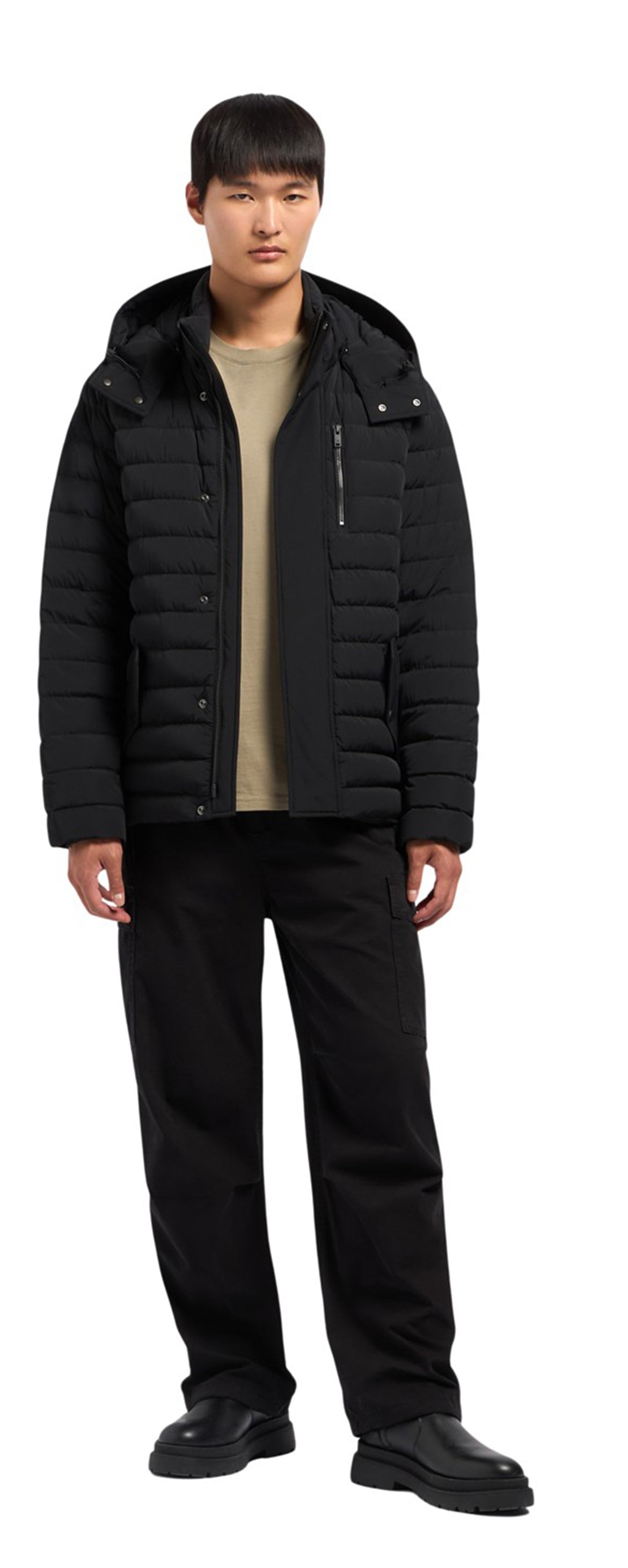 A man in a black puffer jacket with a hood and black pants and shoes.