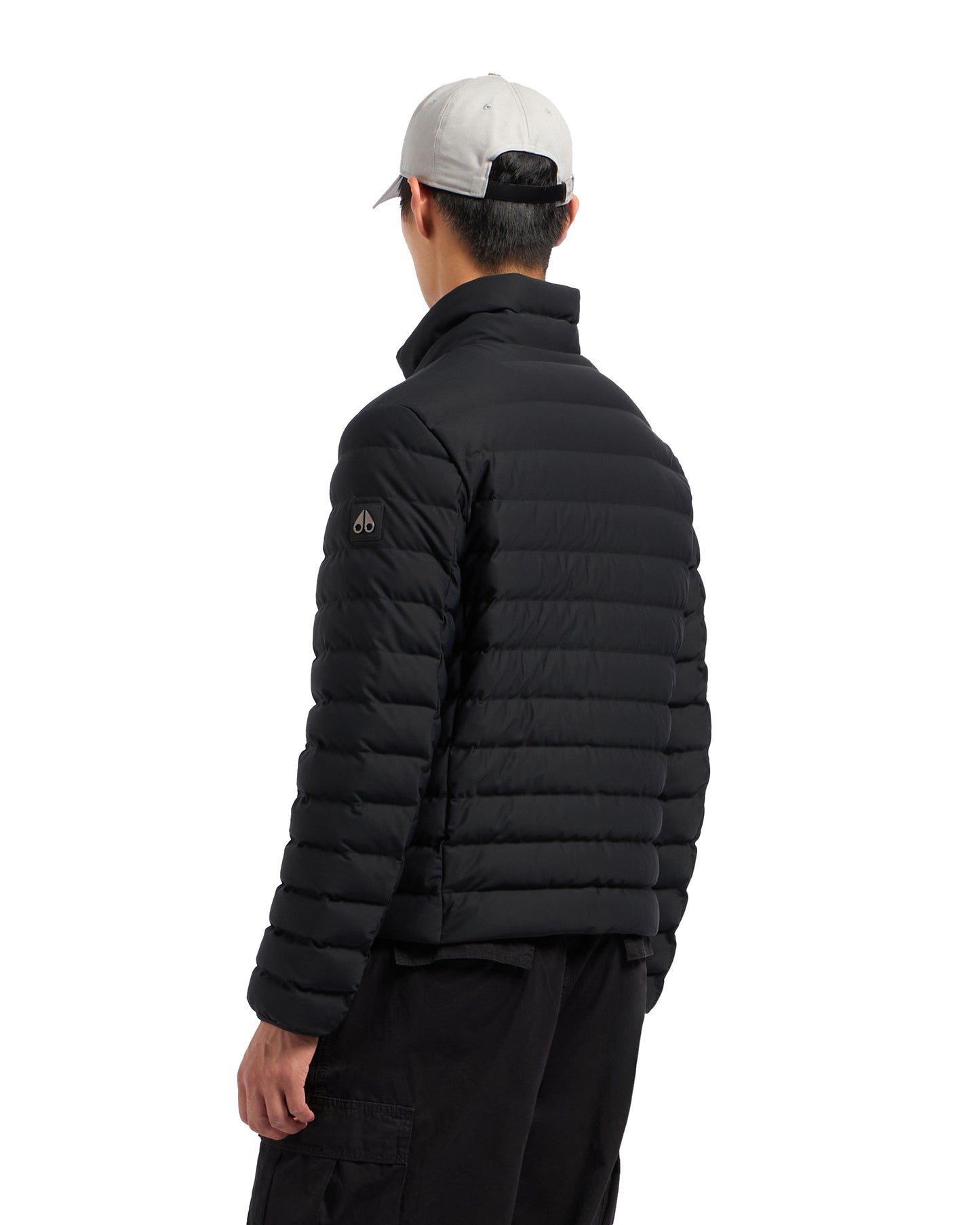 A person from the back wearing a black padded jacket and a light gray cap.